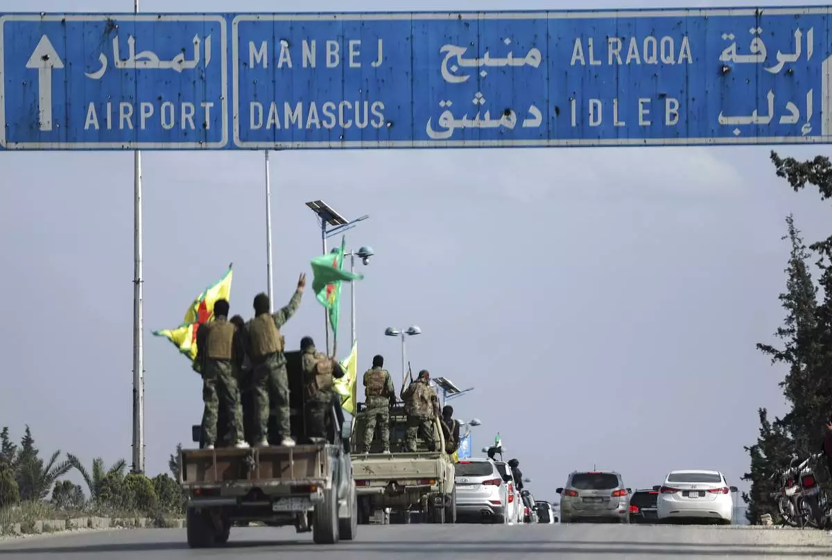 U.S.-backed Kurdish fighters stands on their vehicles, as they withdraw from two neighbourhoods in Syria's northern city of Aleppo as part of a deal with the Syrian central government, in Aleppo, Syria, Friday, April 4, 2025. (AP Photo/Ghaith Alsayed)
