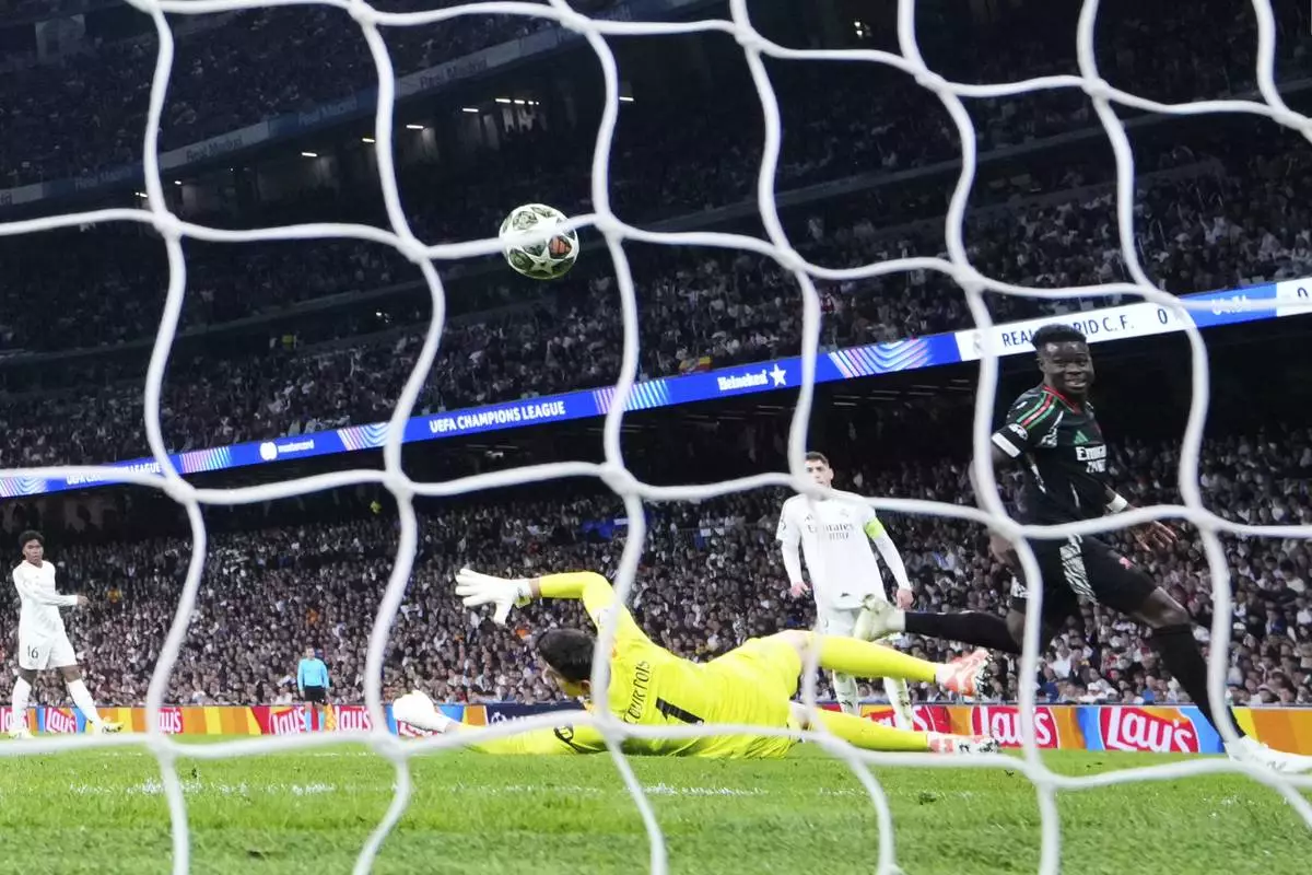 Arsenal's Bukayo Saka, right, scores the opening goal during the Champions League quarterfinals second leg soccer match between Real Madrid and Arsenal at the Santiago Bernabeu stadium in Madrid, Wednesday, April 16, 2025. (AP Photo/Manu Fernandez)