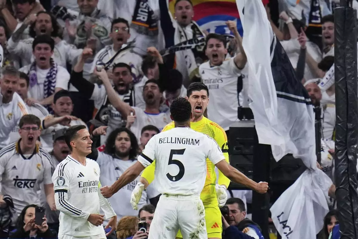 Real Madrid's goalkeeper Thibaut Courtois, right, reacts after saving a penalty shot by Arsenal's Bukayo Saka during the Champions League quarterfinals second leg soccer match between Real Madrid and Arsenal at the Santiago Bernabeu stadium in Madrid, Wednesday, April 16, 2025. (AP Photo/Manu Fernandez)