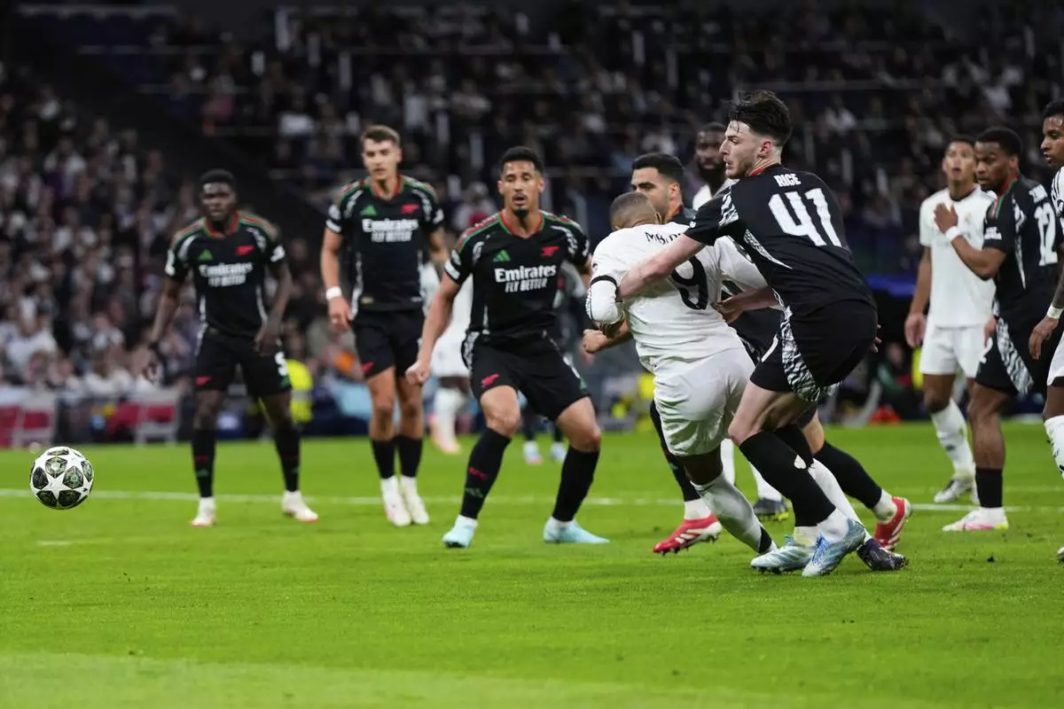 Arsenal's Declan Rice, center right, grabs Real Madrid's Kylian Mbappe in the box during the Champions League quarterfinals second leg soccer match between Real Madrid and Arsenal at the Santiago Bernabeu stadium in Madrid, Wednesday, April 16, 2025. (AP Photo/Manu Fernandez)
