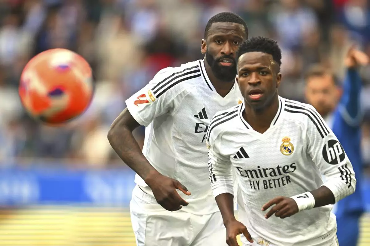 Real Madrid's Vinicius Junior, right and Antonio Rudiger chase the ball during a Spanish La Liga soccer match between Alaves and Real Madrid at the Mendizorroza stadium in Vitoria, Spain, Sunday April 13, 2025. (AP Photo/Miguel Oses)