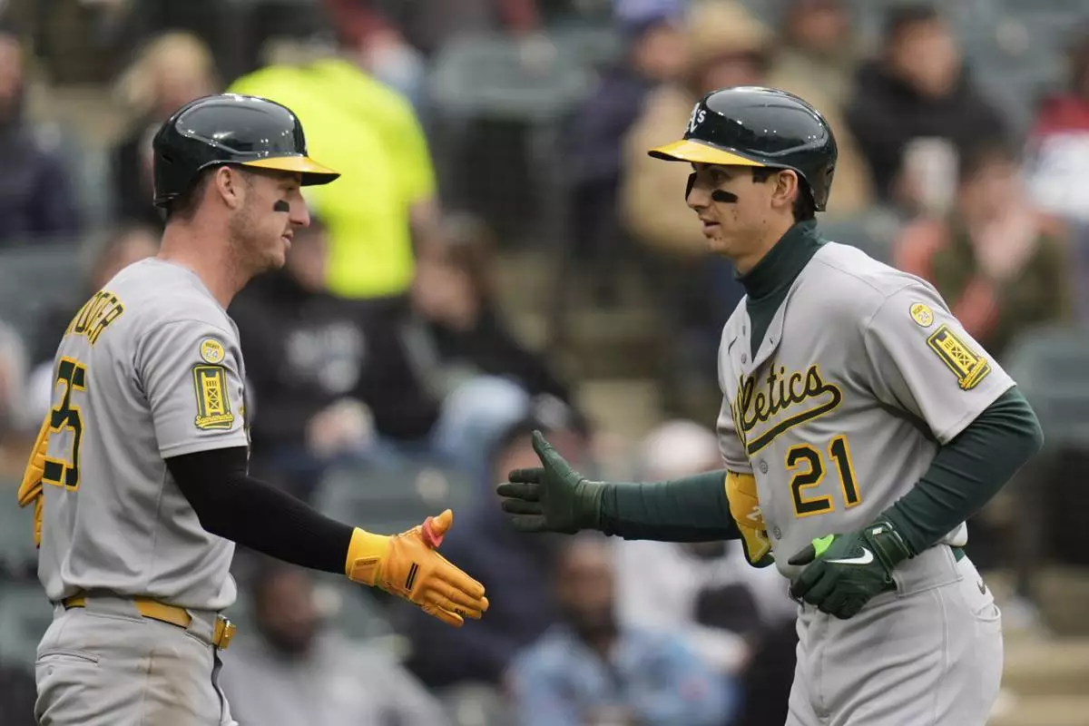 Athletics' Tyler Soderstrom (21) slaps hands with Brent Rooker, left, after hitting a home run during the seventh inning of a baseball game against the Chicago White Sox, Thursday, April 17, 2025, in Chicago. (AP Photo/Erin Hooley)
