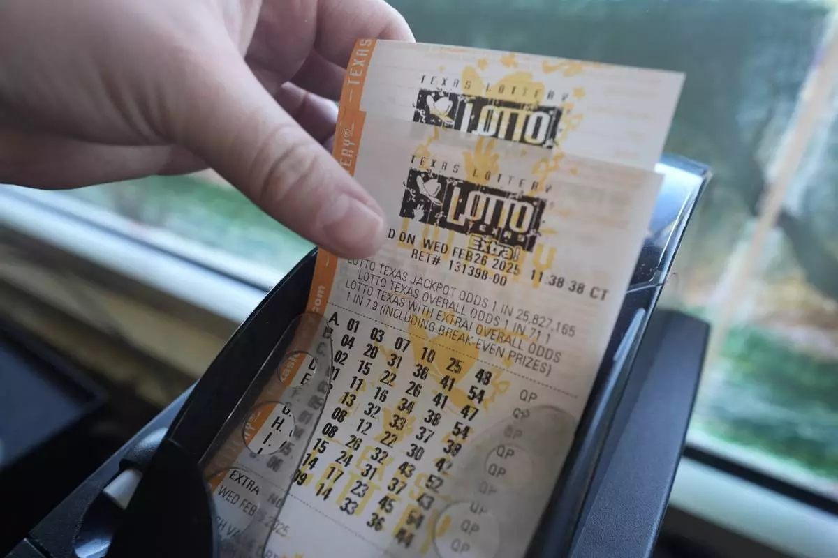 FILE - Edith Patlan grabs printed tickets from a Texas Lottery sales terminal at Fuel City in Dallas, Wednesday, Feb. 26, 2025. (AP Photo/LM Otero, File)