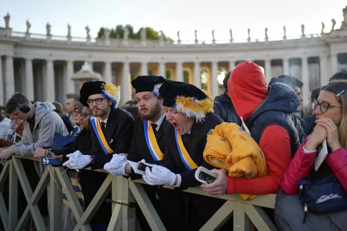 A man yawns as people arrive in St. Peter's Square ahead of the funeral of Pope Francis at the Vatican, Saturday, April 26, 2025. (AP Photo/Andreea Alexandru)