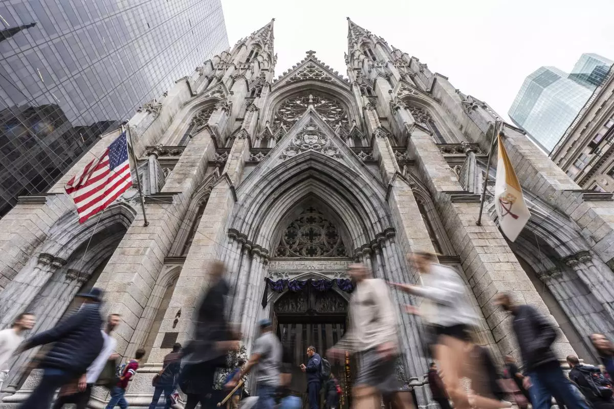 People walk past St. Patrick's Cathedral as dark drapes hang over the doorway before a memorial mass for the late Pope Francis, Saturday, April 26, 2025, in New York. (AP Photo/Julia Demaree Nikhinson)