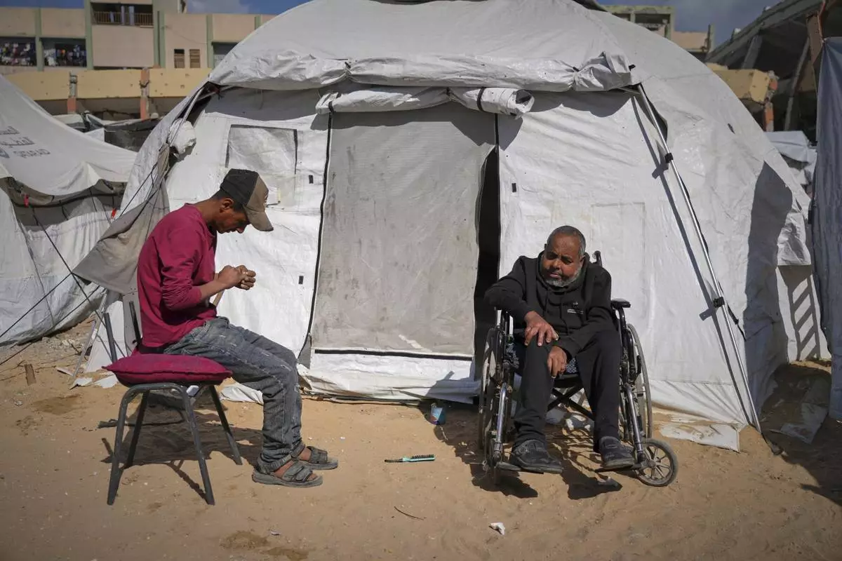 Mohamed Attiya, 54, right, and his son, Wasem, sit in front of their tent before heading to Shifa hospital for a dialysis session in Gaza City, Monday, April 14, 2025. (AP Photo/Jehad Alshrafi)