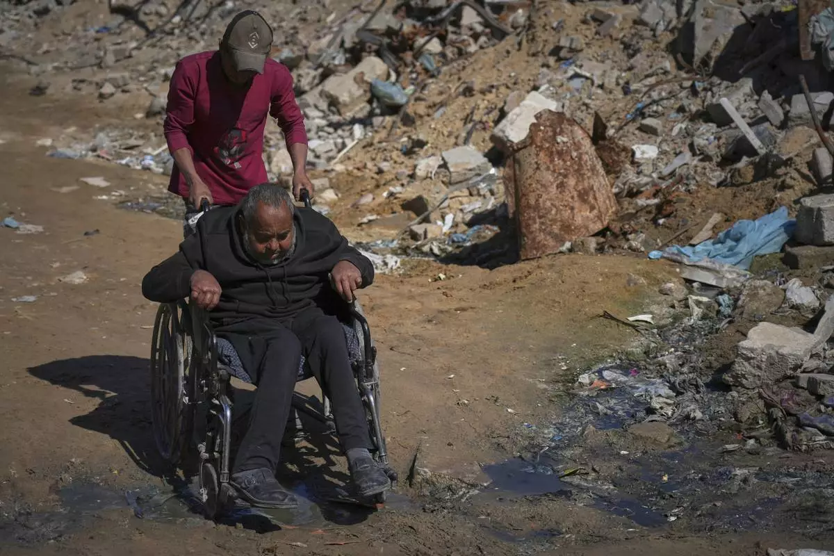 Wasem Attiya pushes his father, Mohamed, 54, in a wheelchair as they head to Shifa hospital in Gaza City for a dialysis session, Monday, April 14, 2025. (AP Photo/Jehad Alshrafi)