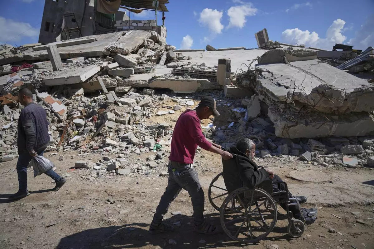 Wasem Attiya pushes his father, Mohamed, 54, in a wheelchair as they head to Shifa hospital in Gaza City for a dialysis session, Monday, April 14, 2025. (AP Photo/Jehad Alshrafi)
