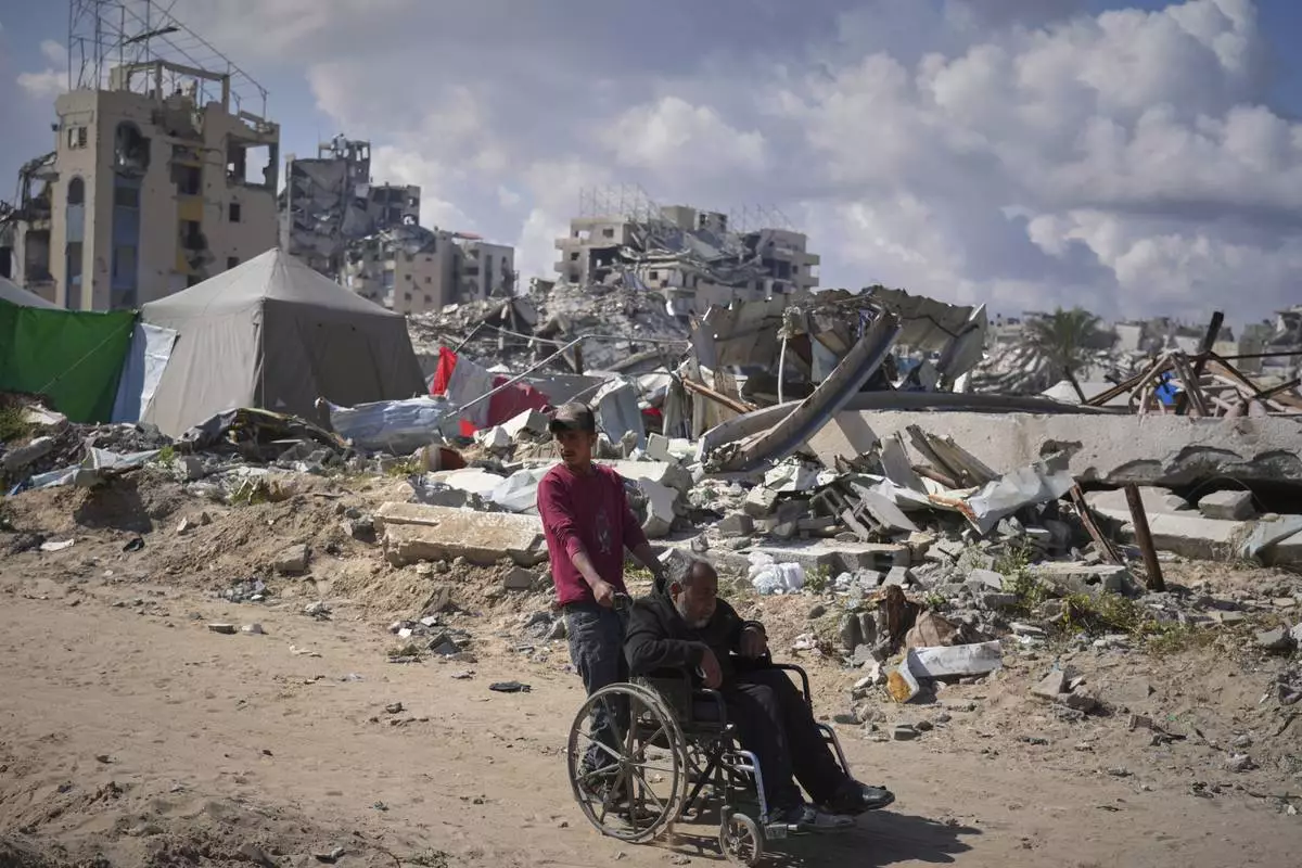 Wasem Attiya pushes his father, Mohamed, 54, in a wheelchair as they head to Shifa hospital in Gaza City for a dialysis session, Monday, April 14, 2025. (AP Photo/Jehad Alshrafi)