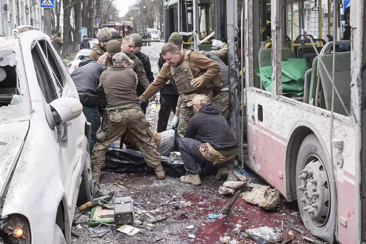 Ukrainian servicemen carry a dead body from a trolleybus after a Russian missile strike on Sumy, Ukraine, Sunday, April 13, 2025. (AP Photo/Volodymyr Hordiienko)
