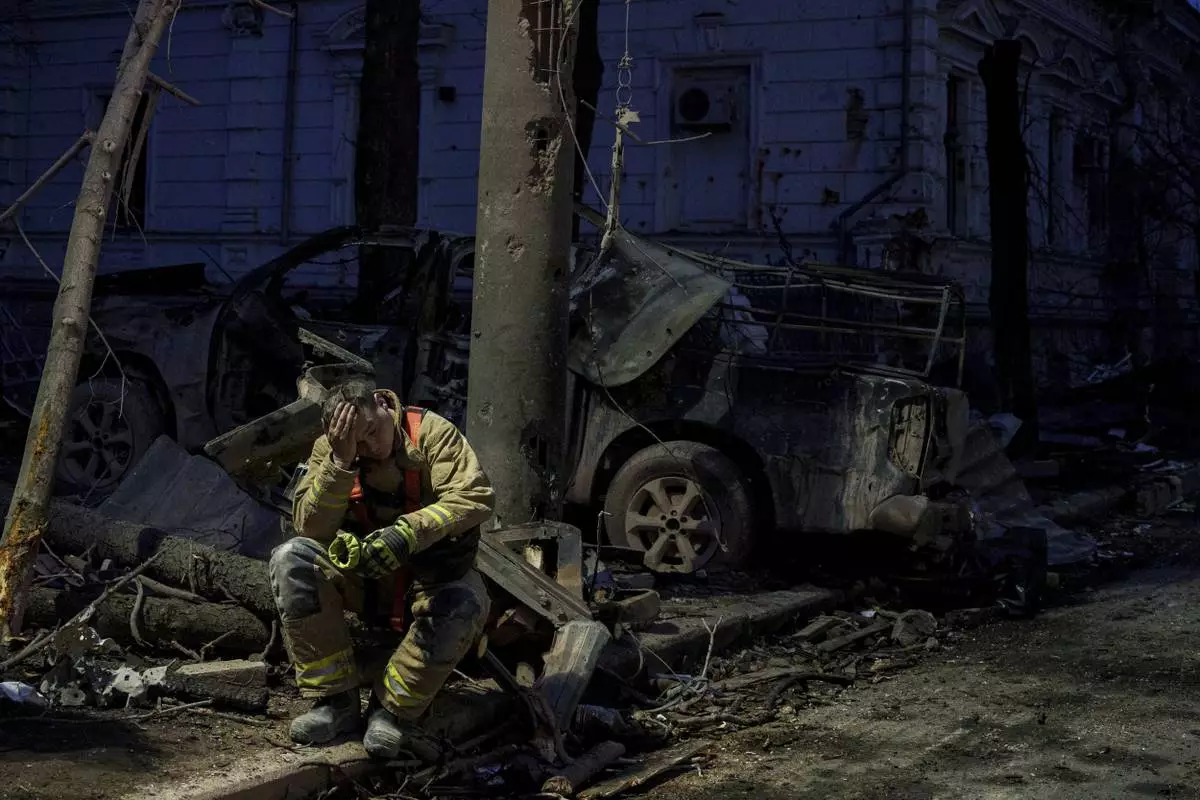 A rescue worker rests near university building destroyed by a Russian missile strike on Sumy, Ukraine, Sunday, April 13, 2025. (AP Photo/Evgeniy Maloletka)