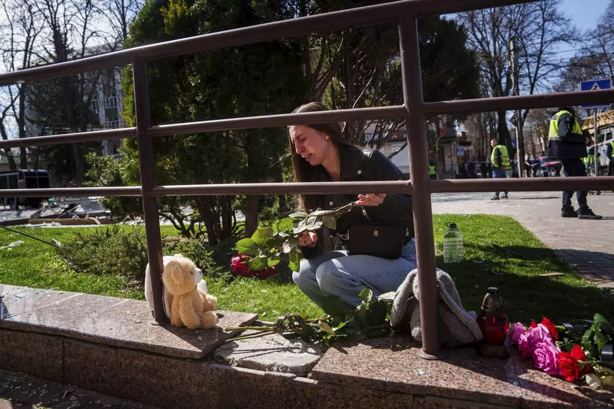 Kateryna Sitak, 23, a teacher, cries while laying flowers and toys on a site of a Russian missile strike in Sumy, Ukraine, Monday, April 14, 2025. (AP Photo/Evgeniy Maloletka)