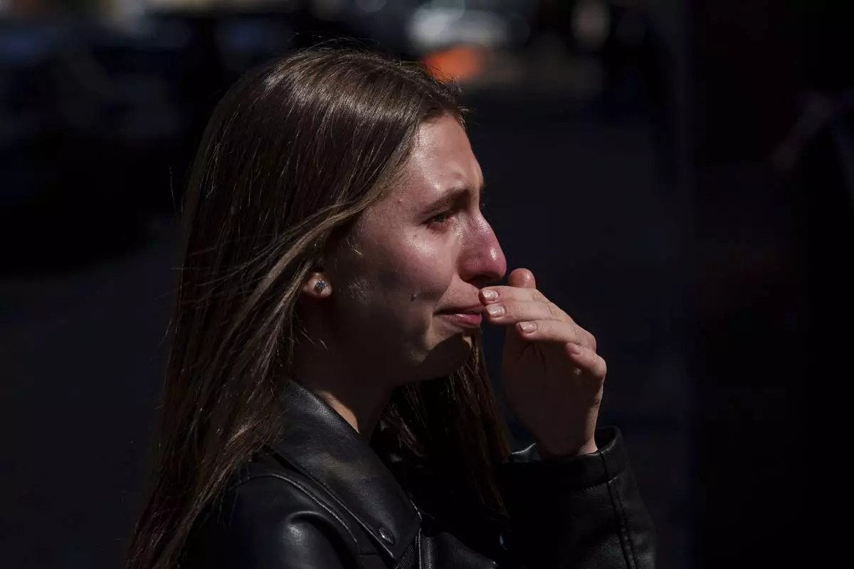Kateryna Sitak, 23, a teacher, cries after laying flowers and toys on a site of a Russian missile strike in Sumy, Ukraine, Monday, April 14, 2025. (AP Photo/Evgeniy Maloletka)