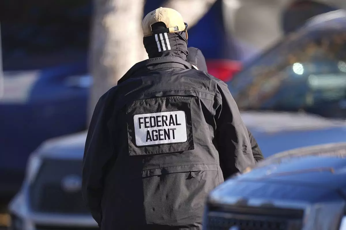 FILE - A member of law enforcement stand near an entrance to an apartment complex during a raid by federal agents Feb. 5, 2025, in east Denver. (AP Photo/David Zalubowski, File)