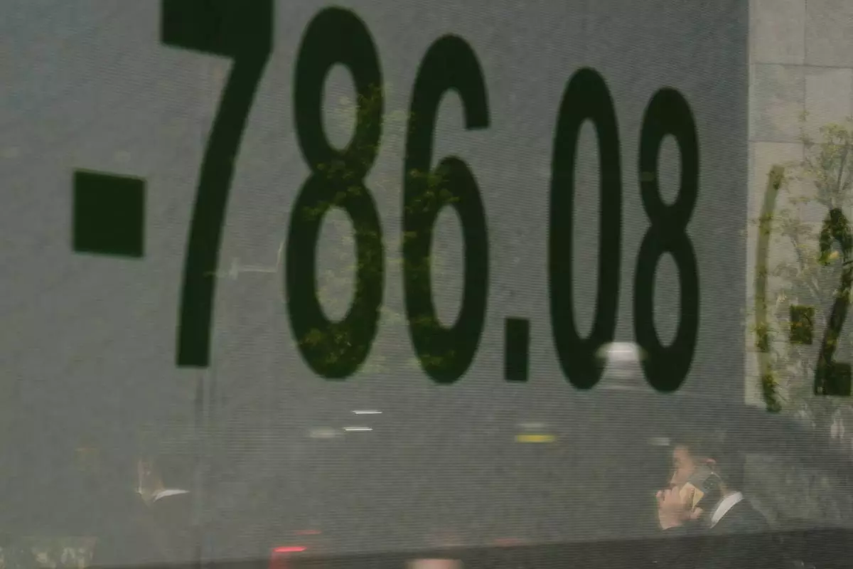 A man talking on the phone is reflected on a screen showing Japan's Nikkei 225 index at a securities firm in Tokyo, Wednesday, April 9, 2025. (AP Photo/Hiro Komae)