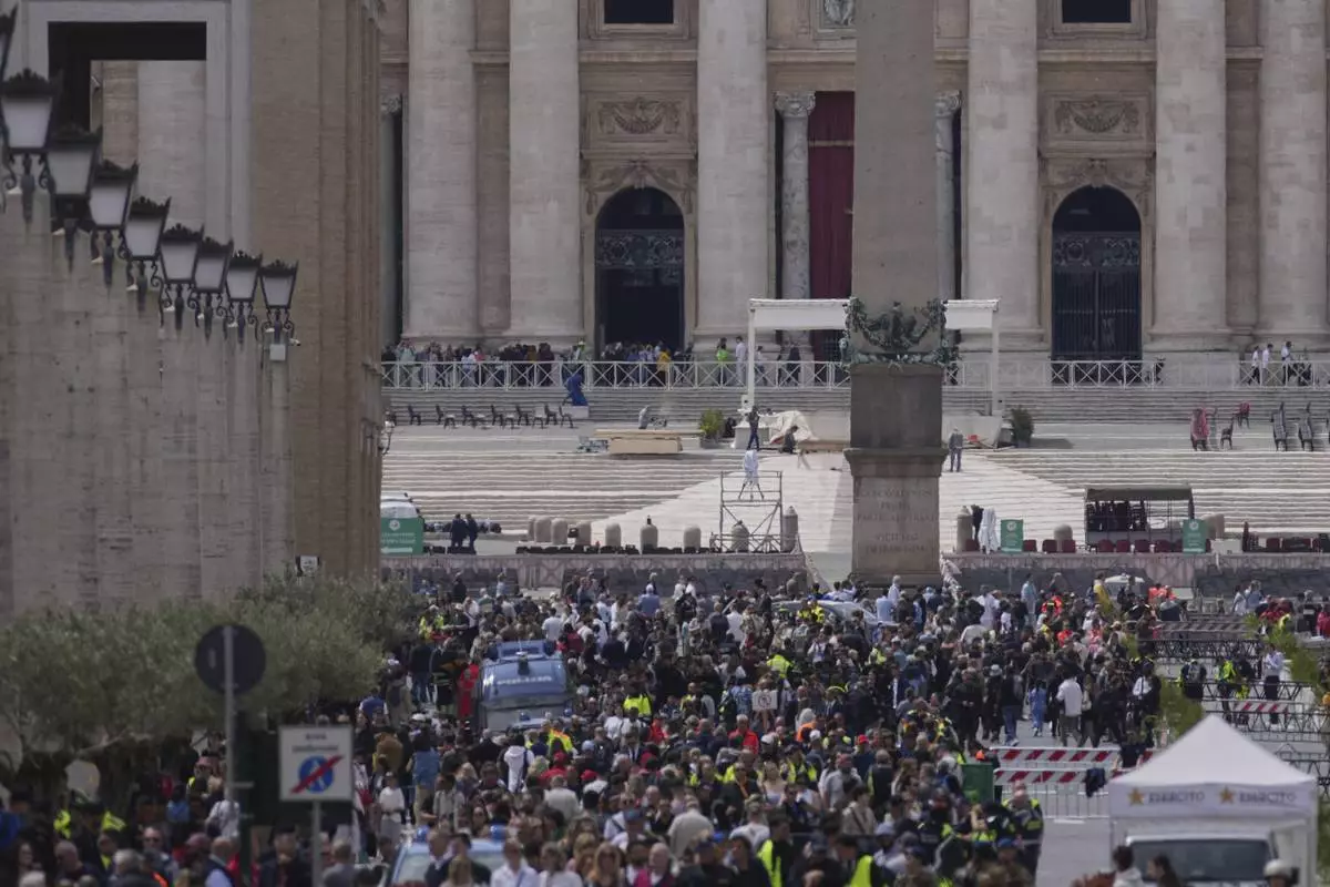 People line up along Via della Conciliazione avenue to view Pope Francis lying in state inside St. Peter's Basilica, seen in the background, at the Vatican, Thursday, April 24, 2025. (AP Photo/Andrew Medichini)