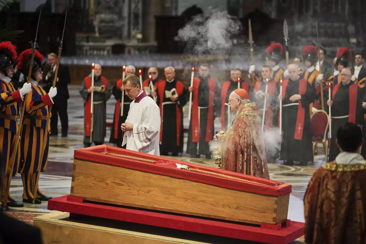 Cardinal Camerlengo Kevin Joseph Farrell, center right, spreads incense around the body of Pope Francis inside St. Peter's Basilica at the Vatican, Wednesday, April 23, 2025, where he will lie in state for three days. (AP Photo/Alessandra Tarantino)