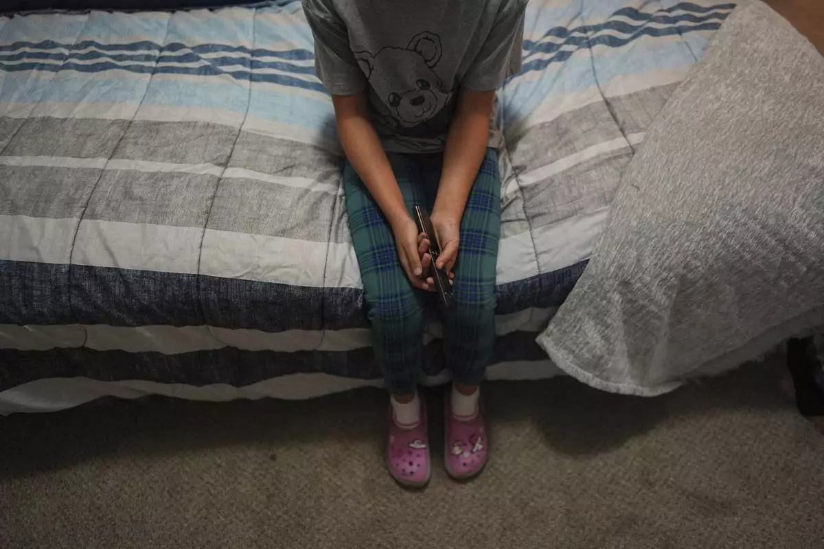 A 9-year-old girl with Temporary Protected Status, or TPS, who was born in Venezuela, but who fluently speaks only English and is in the gifted program at her school, watches TV in her family's apartment, Saturday, April 5, 2025, in Doral, Fla. (AP Photo/Rebecca Blackwell)