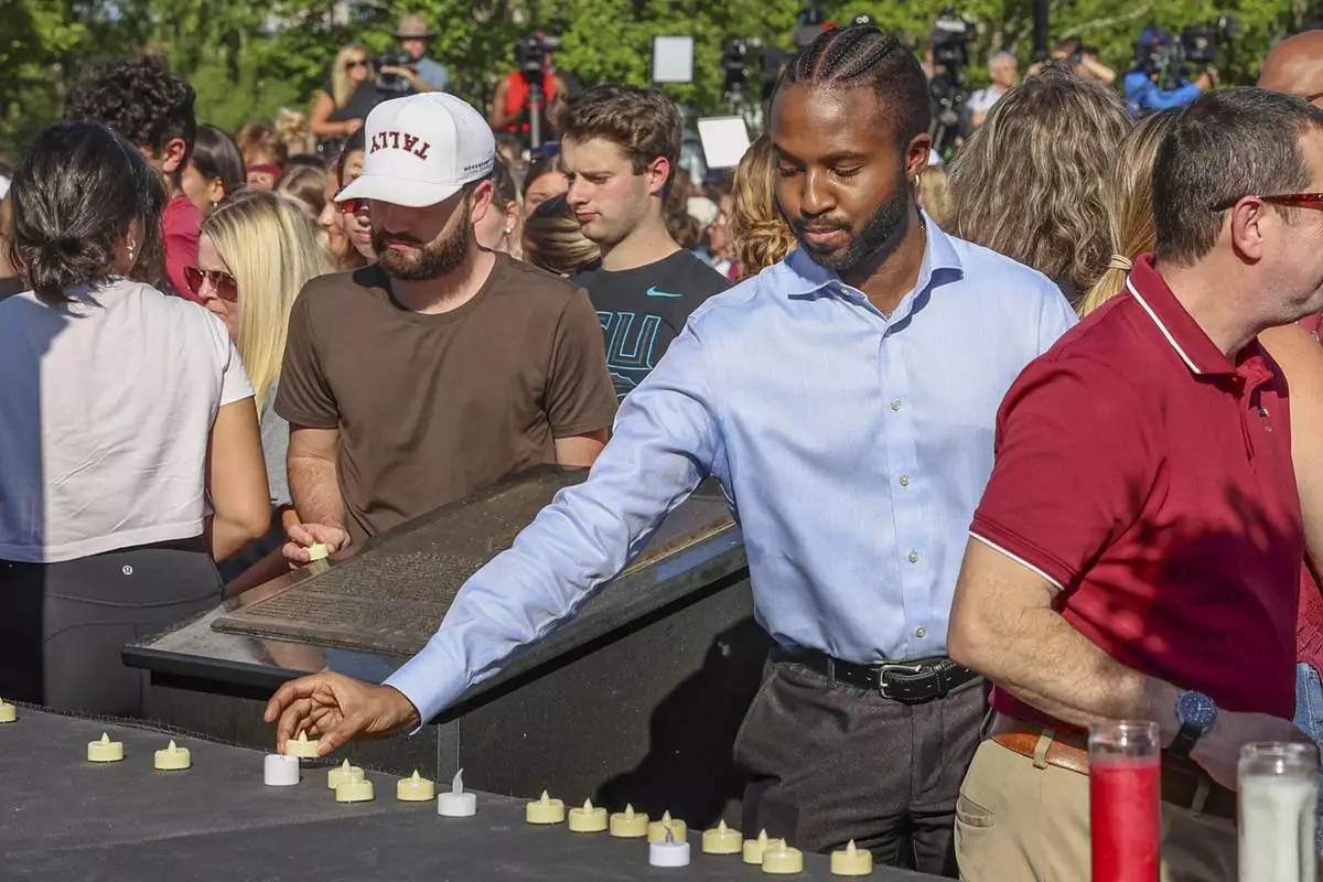 The day after an active shooter on campus Florida State students place electronic candles on a platform during a vigil on campus at Langford Green, Tallahassee, Fla., Friday, April 18, 2025. (AP Photo/Gary McCullough)