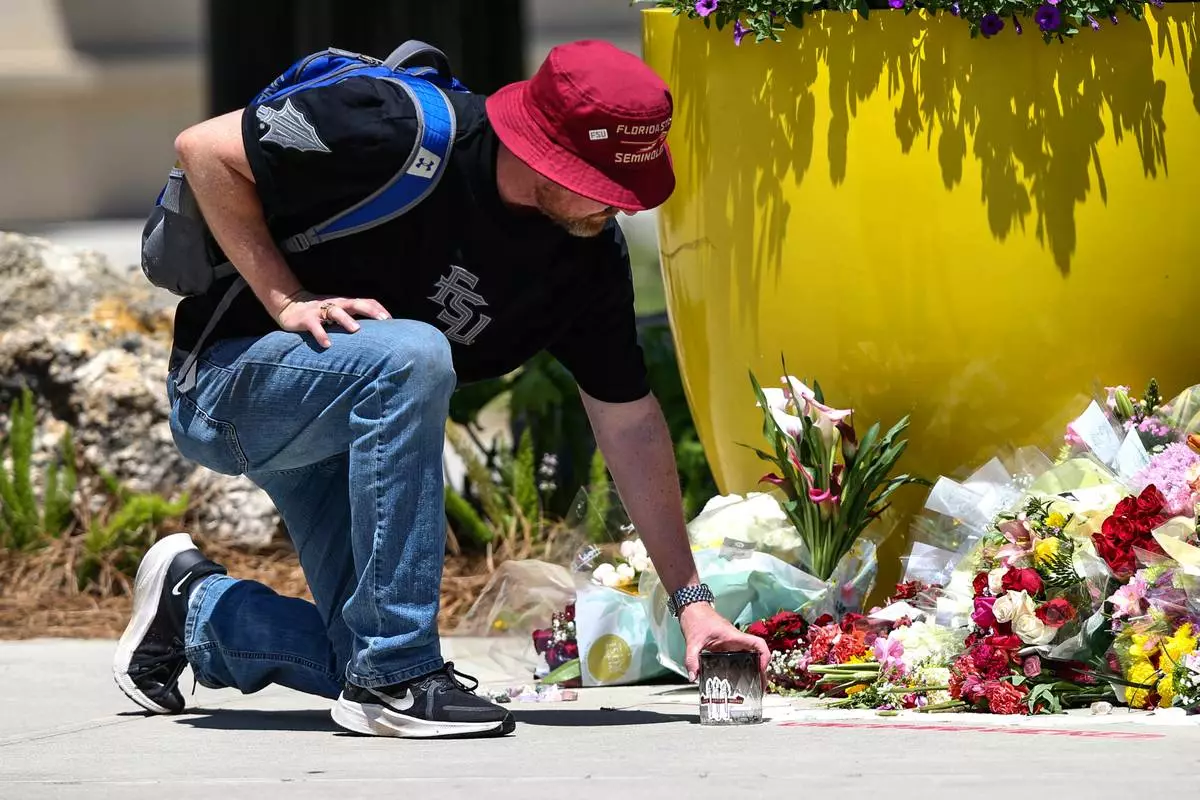 A student places a candle near the Florida State Student Union building, Tallahassee, Fla., Friday, April 18, 2025. (AP Photo/Gary McCullough)