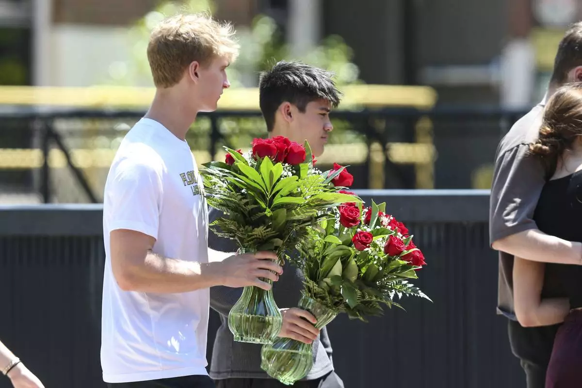 Students carry flowers near the Florida State Student Union building, Tallahassee, Fla., Friday, April 18, 2025. (AP Photo/Gary McCullough)