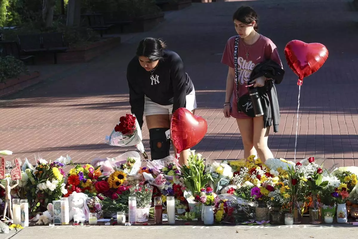 Students place flowers on a stretch of sidewalk near the center of the Florida State campus in sight of the Student Union building, Tallahassee, Fla., Friday, April 18, 2025. (AP Photo/Gary McCullough)
