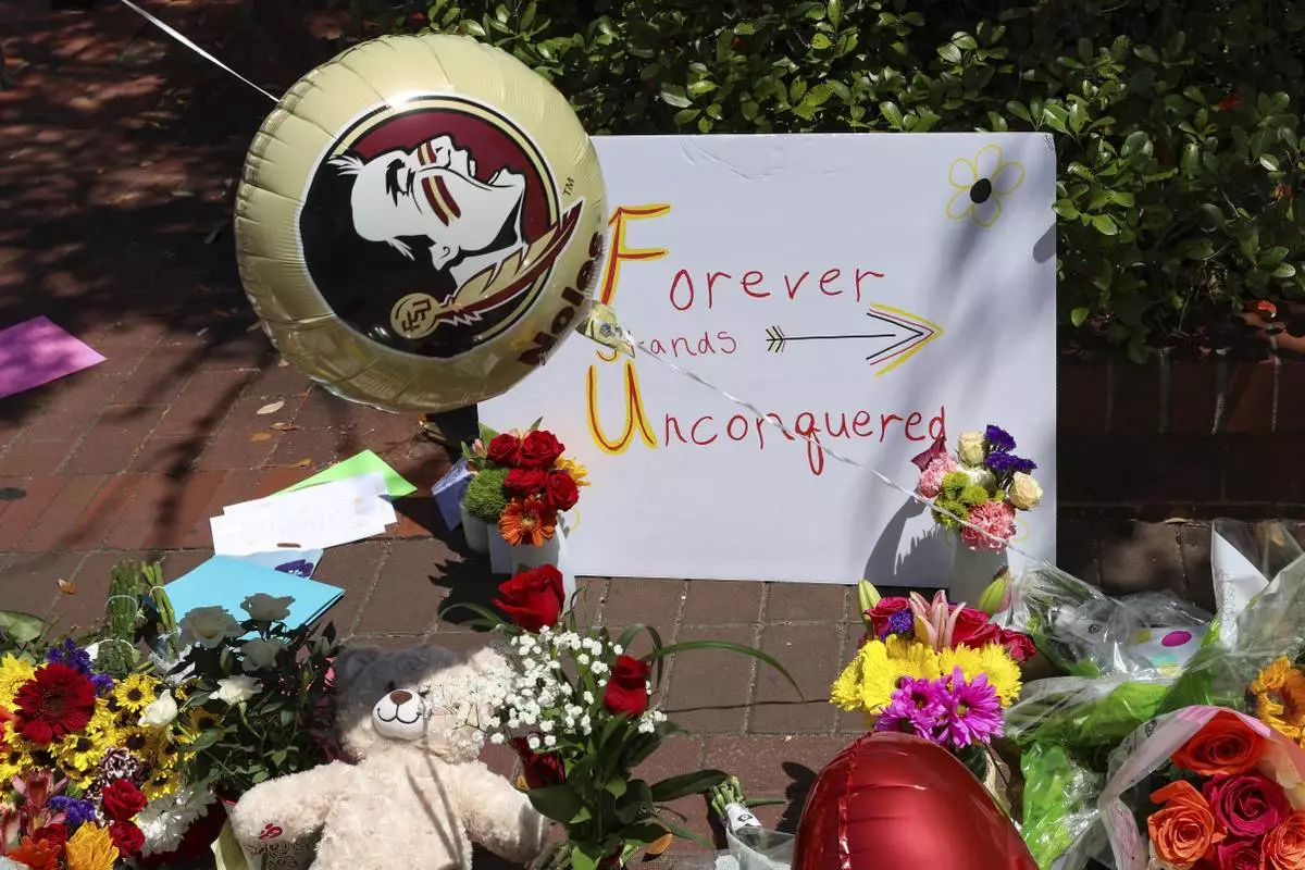 A sign that reads "Forever Stands Unconquered," is placed among flowers near the Florida State Student Union building, Tallahassee, Fla., Friday, April 18, 2025. (AP Photo/Gary McCullough)