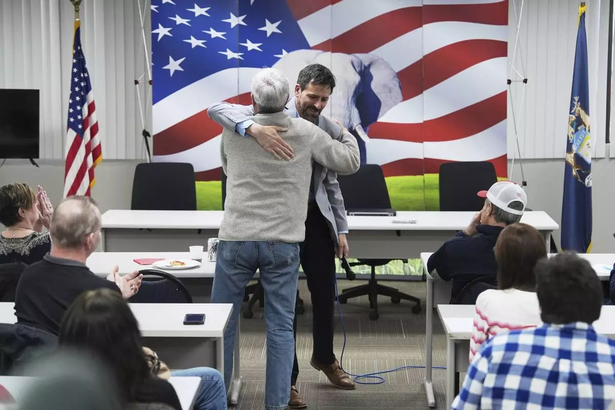Ryan Kelley, right, hugs William "Hank" Choate during his talk at the Jackson County Republican headquarters Thursday, April 10, 2025, in Jackson, Mich. (AP Photo/Paul Sancya)