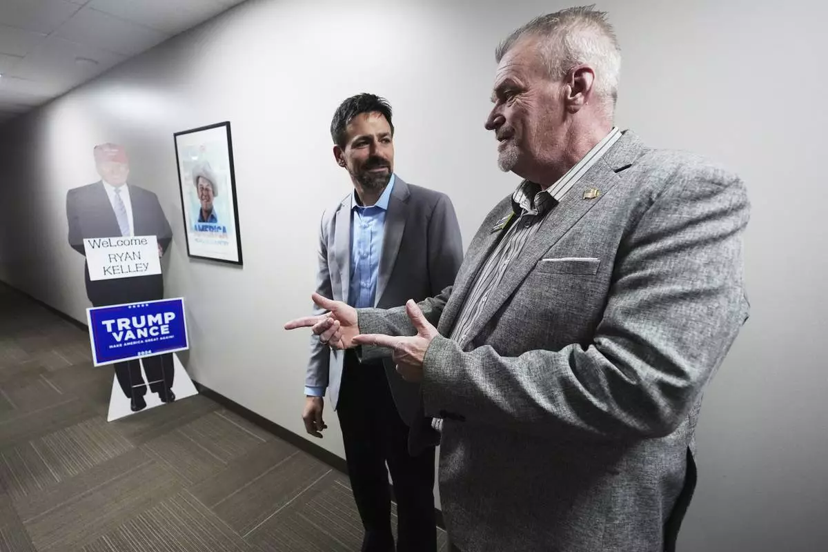 Ryan Kelley, left, talks with Russ Jennings, chairman of the Jackson County Republican Committee, before speaking, Thursday, April 10, 2025, in Jackson, Mich. (AP Photo/Paul Sancya)