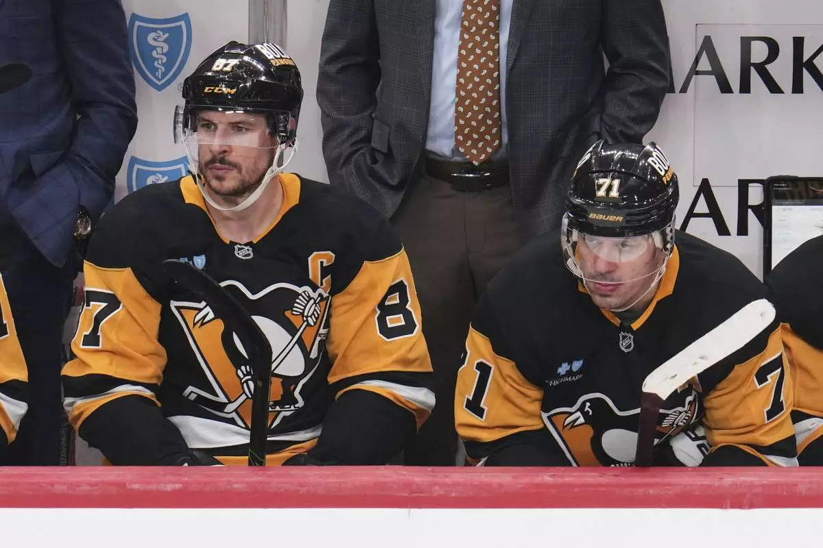 Pittsburgh Penguins' Sidney Crosby (87), and Evgeni Malkin sit on the bench during the third period of an NHL hockey game against the Boston Bruins in Pittsburgh, Sunday, April 13, 2025. (AP Photo/Gene J. Puskar)