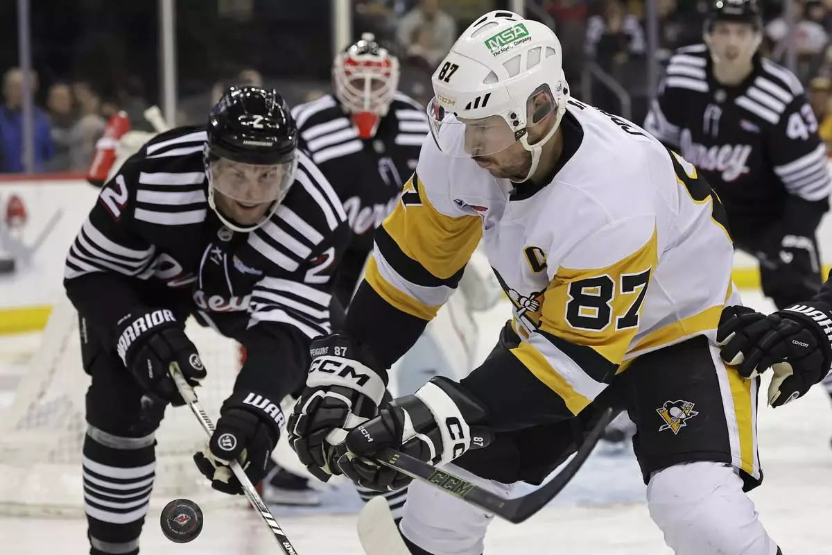 Pittsburgh Penguins center Sidney Crosby (87) battles for the puck with New Jersey Devils defenseman Brian Dumoulin in the third period of an NHL hockey game Friday, April 11, 2025, in Newark, N.J. (AP Photo/Adam Hunger)
