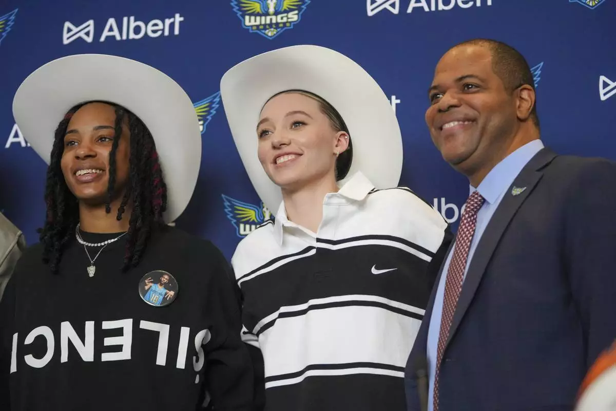 Dallas Wings' Paige Bueckers, center, selected No. 1 overall in the WNBA basketball draft, and Aziaha James, selected No. 12 overall, sport a cowboy hats gifted to them while posing for photographs with Dallas Mayor Eric Johnson during an introductory press conference Wednesday, April 23, 2025, in Dallas. (AP Photo/Julio Cortez)