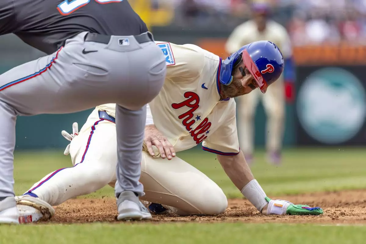 Philadelphia Phillies' Bryce Harper is safe on a pickoff attempt before Miami Marlins first baseman Matt Mervis can make the tag in the third inning of a baseball game, Saturday, April 19, 2025, in Philadelphia. (AP Photo/Laurence Kesterson)