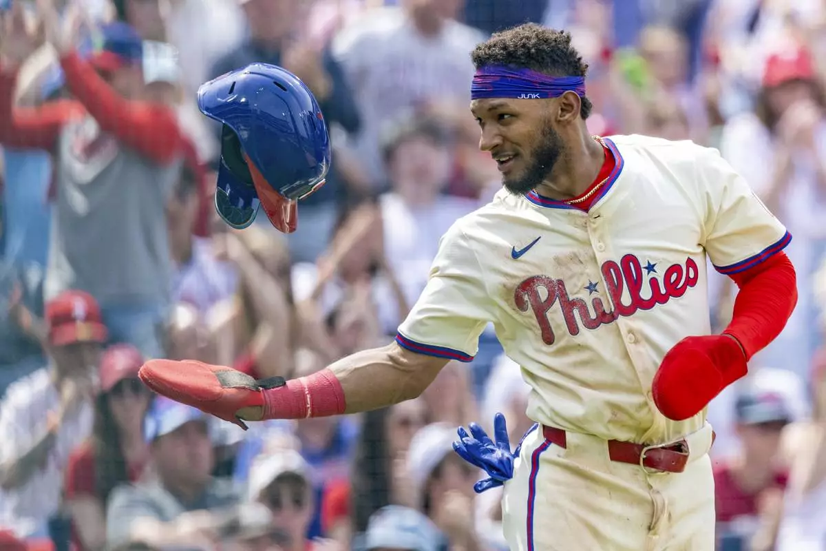 Philadelphia Phillies' Johan Rojas tosses his helmet after scoring on an RBI double by Bryson Stott in the fourth inning of a baseball game against the Miami Marlins, Saturday, April 19, 2025, in Philadelphia. (AP Photo/Laurence Kesterson)