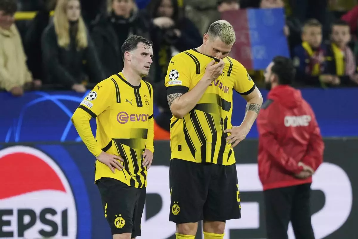 Dortmund's Niklas Suele, right, and Dortmund's Pascal Gross react at the end of the Champions League quarterfinals second leg soccer match between Borussia Dortmund and Barcelona, at the Signa-Iduna Park in Dortmund, Germany, Tuesday, April 15, 2025. (AP Photo/Martin Meissner)