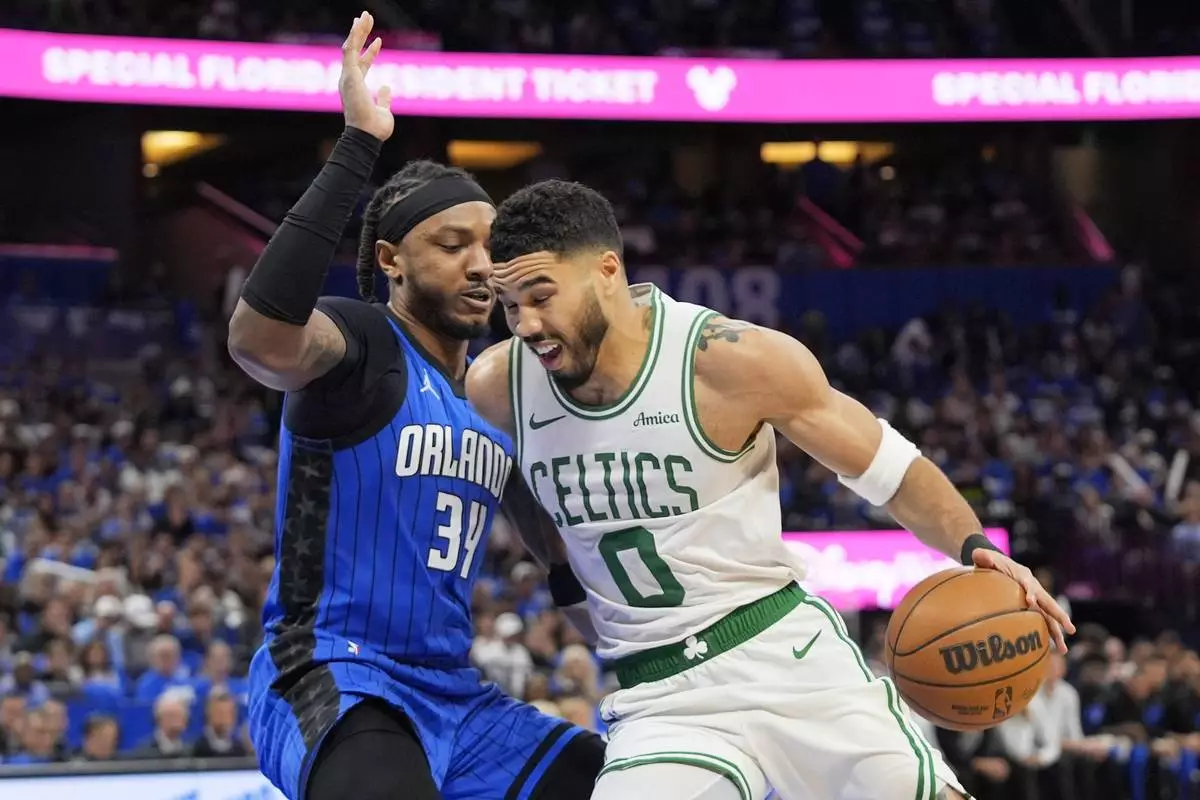 Boston Celtics forward Jayson Tatum (0) drives past Orlando Magic center Wendell Carter Jr. (34) during the first half in game 3 of a first-round NBA playoff basketball series,, Friday, April 25, 2025, in Orlando, Fla. (AP Photo/John Raoux)