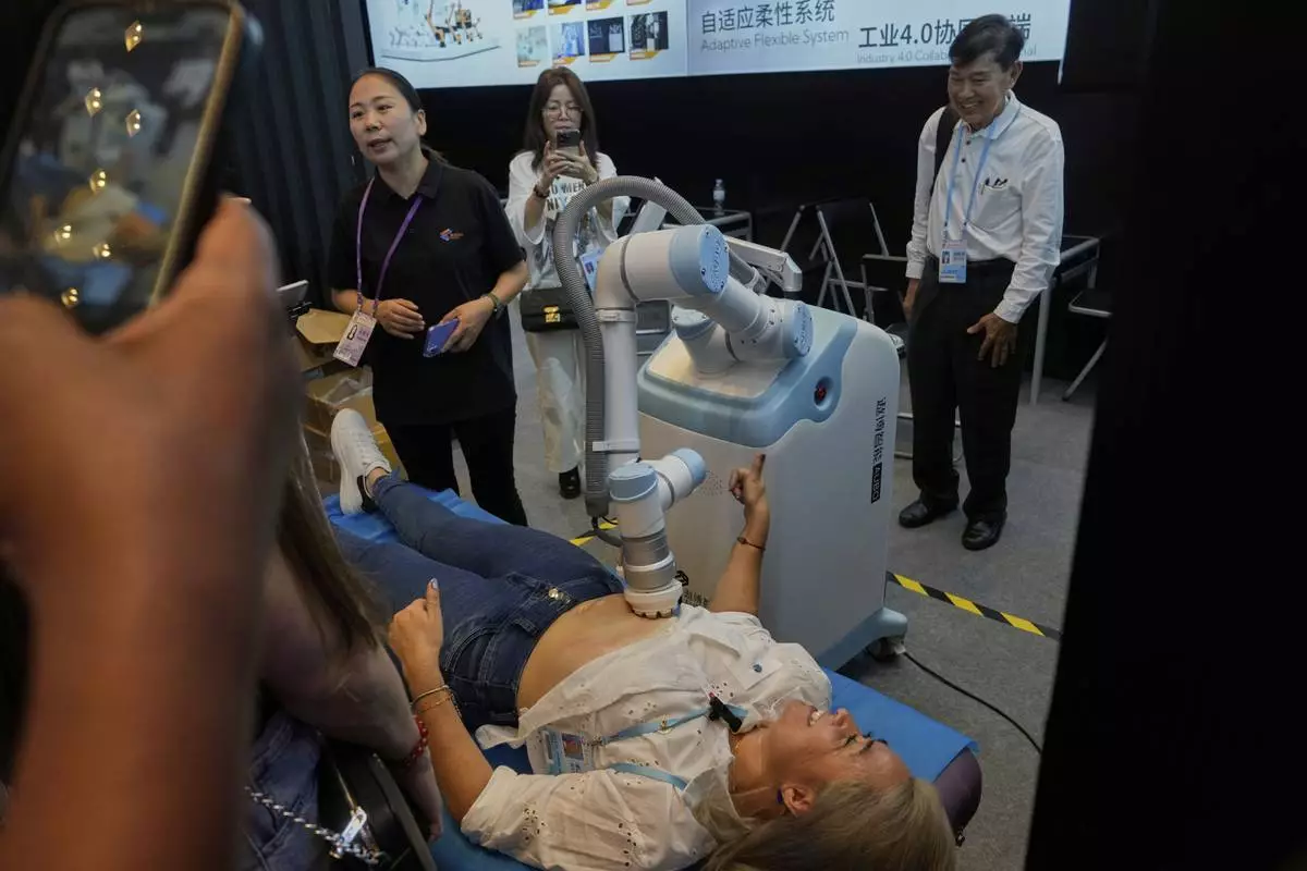 A visitor tests the AUBO therapy robot at the the 137th Canton Fair in Guangzhou in southern China's Guangdong province on Wednesday, April 16, 2025. (AP Photo/Ng Han Guan)