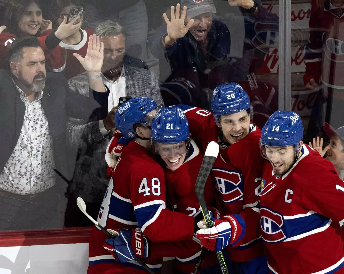 Montreal Canadiens' Kaiden Guhle (21) celebrates his goal against the Carolina Hurricanes with Lane Hutson (48), Juraj Slafkovsky (20) and Nick Suzuki (14) during second period NHL hockey action in Montreal on Wednesday, April 16, 2025. (Allen McInnis/The Canadian Press via AP)