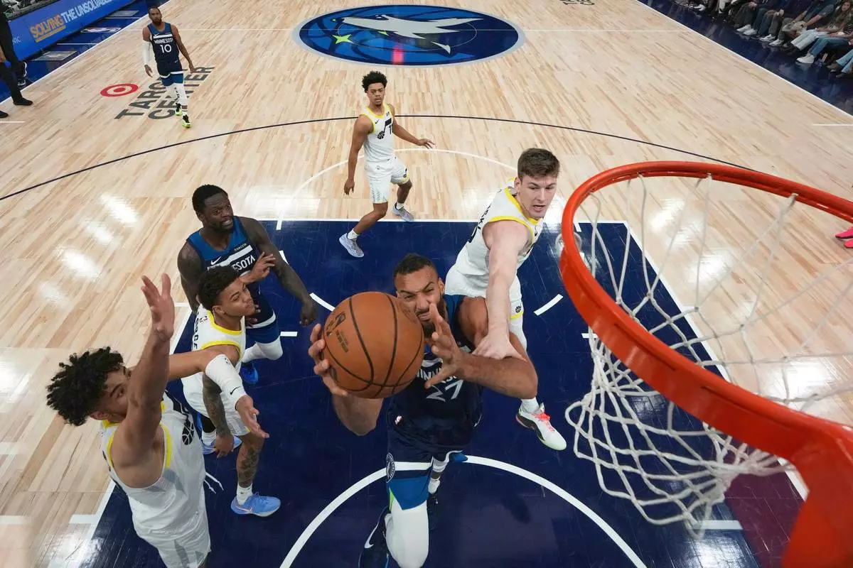 Minnesota Timberwolves center Rudy Gobert (27) goes up for a shot as Utah Jazz forward Kyle Filipowski, right, defends during the first half of an NBA basketball game, Sunday, April 13, 2025, in Minneapolis. (AP Photo/Abbie Parr)