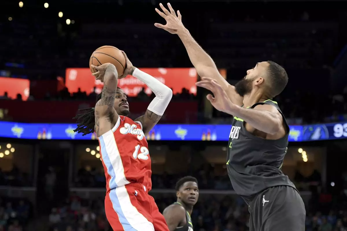 Memphis Grizzlies guard Ja Morant (12) handles the ball against Minnesota Timberwolves center Rudy Gobert, right, in the second half of an NBA basketball game Thursday, April 10, 2025, in Memphis, Tenn. (AP Photo/Brandon Dill)