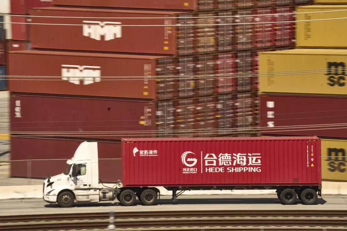 A truck carrying a Hede (Hong Kong) International Shipping Co., Ltd., container moves along the Port of Los Angeles Wednesday, April 9, 2025 in Los Angeles. (AP Photo/Damian Dovarganes)