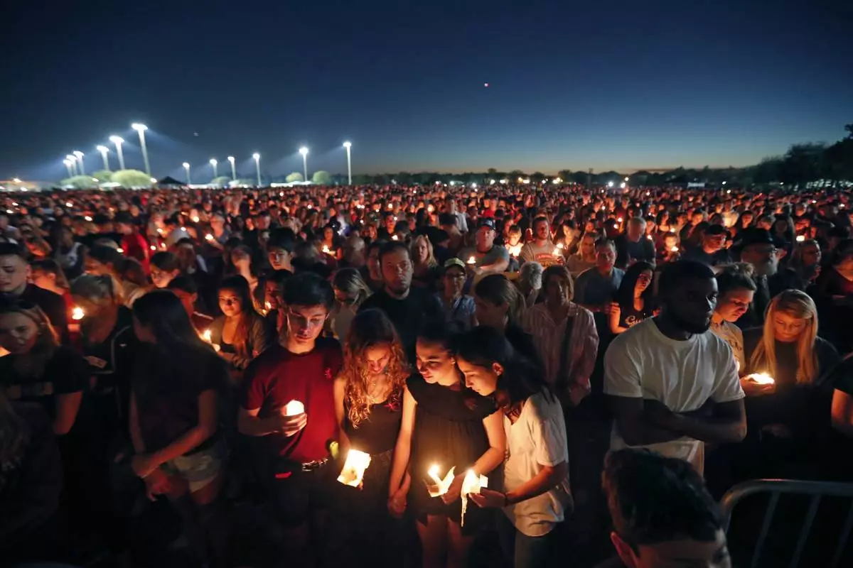 FILE - People attend a candlelight vigil for the victims of a shooting at Marjory Stoneman Douglas High School, in Parkland, Fla., Feb. 15, 2018. (AP Photo/Gerald Herbert, File)