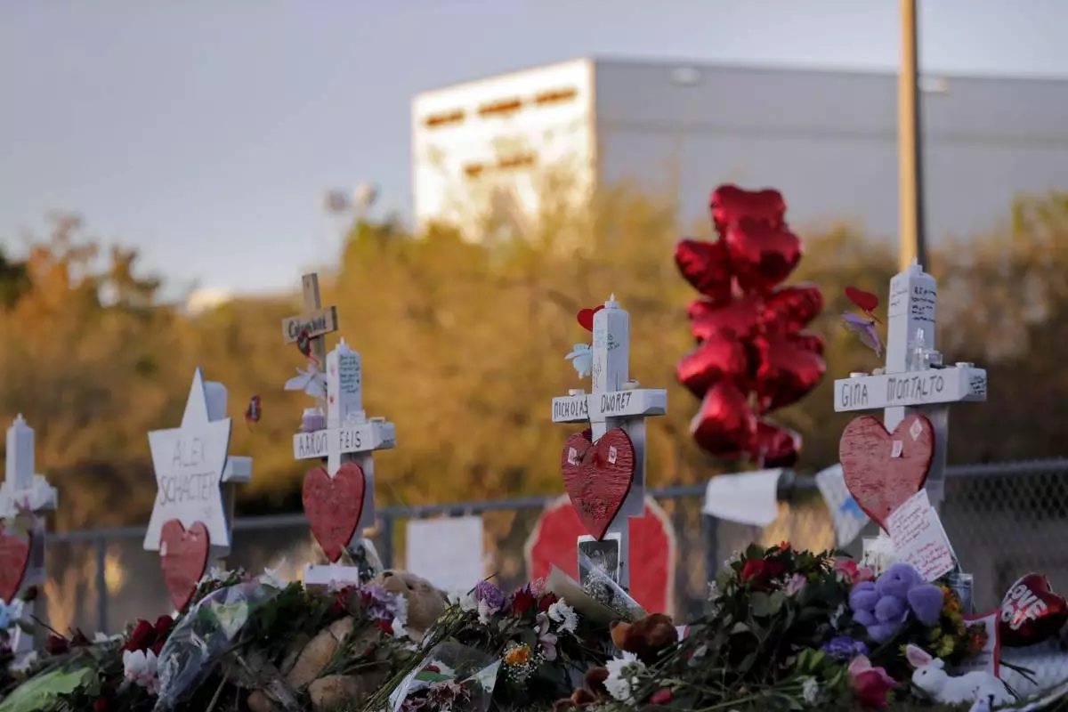 FILE - A memorial is stands outside the Marjory Stoneman Douglas High School where 17 students and faculty were killed in a mass shooting in Parkland, Fla, Feb. 19, 2018. (AP Photo/Gerald Herbert, File)
