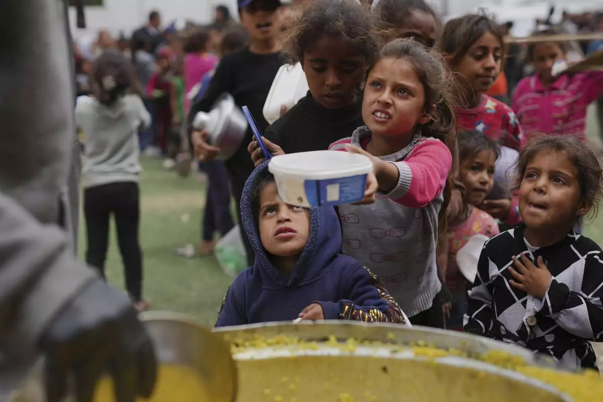 Palestinian children receive donated food at a distribution center in Nuseirat, central Gaza Strip, Friday, April 11, 2025. (AP Photo/Abdel Kareem Hana)