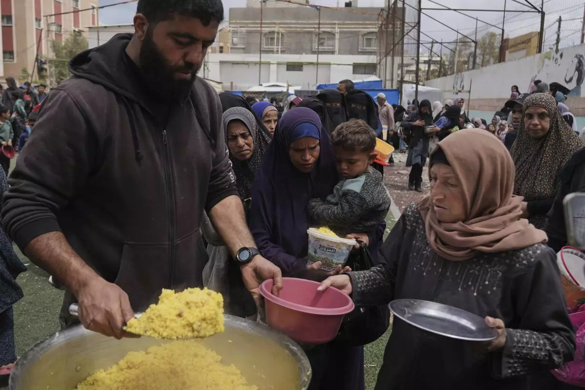 Palestinians receive donated food at a distribution center in Nuseirat, central Gaza Strip, Friday, April 11, 2025. (AP Photo/Abdel Kareem Hana)