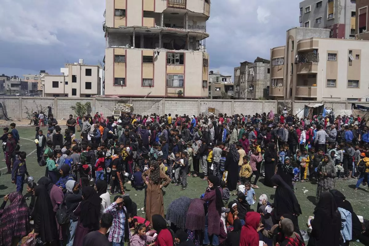 Palestinians wait for donated food at a distribution center in Nuseirat, central Gaza Strip, Friday, April 11, 2025. (AP Photo/Abdel Kareem Hana)