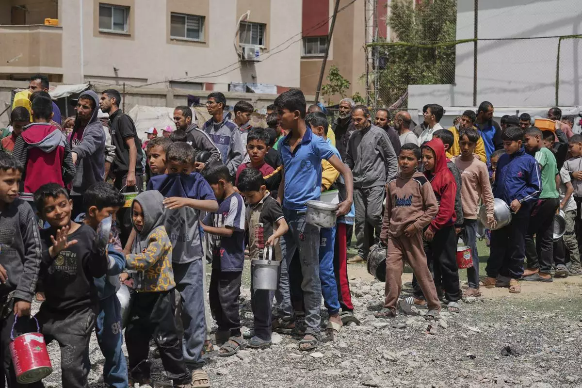 Palestinians wait for donated food at a distribution center in Nuseirat, central Gaza Strip, Friday, April 11, 2025. (AP Photo/Abdel Kareem Hana)