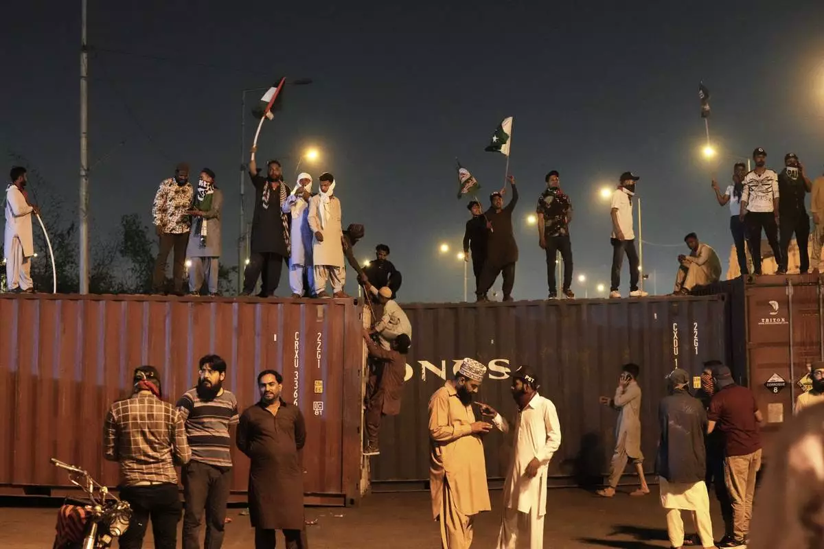 Supporters of the Pakistani religious group "Sunni Tehreek" chant slogans on the shipping containers placed by authorities to stop them for marching towards U.S. consulate during a rally against Israeli airstrikes and to show solidarity with Palestinian people living in Gaza, in Karachi, Pakistan Friday, April 11, 2025. (AP Photo/Fareed Khan)