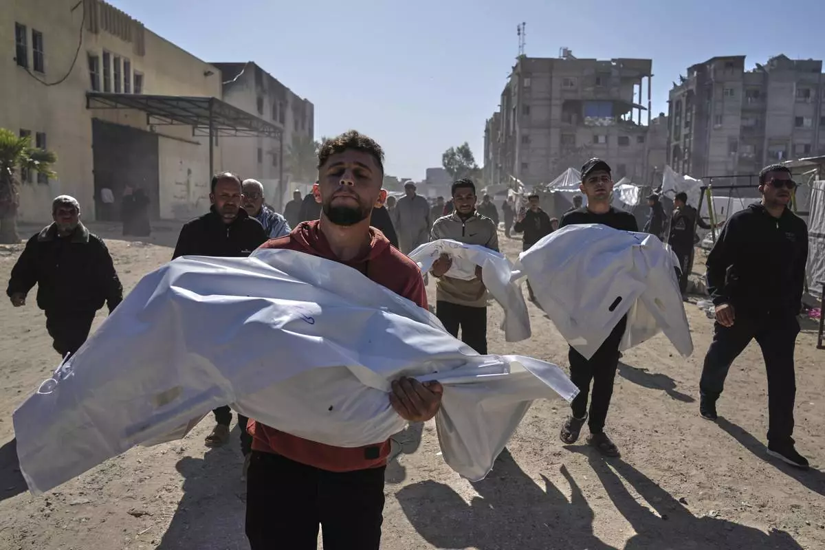 Mourners carry white sacks covering the bodies of members of the Abu Al-Rous family, killed when an Israeli airstrike struck their displacement tent overnight, during their funeral in Khan Younis, southern Gaza Strip, Thursday, April 17, 2025. (AP Photo/Abdel Kareem Hana)