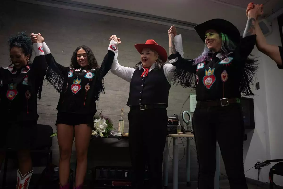 Mexican corridos singer Vivir Quintana joins hands with her band before the introduction of her new album, about violence against women, in Mexico City, Thursday, April 24, 2025. (AP Photo/Aurea Del Rosario)